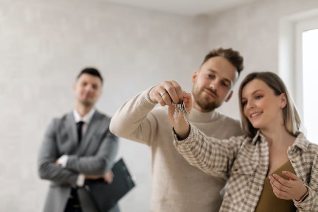 two tenants holding the keys to their rental as a landlord watches
